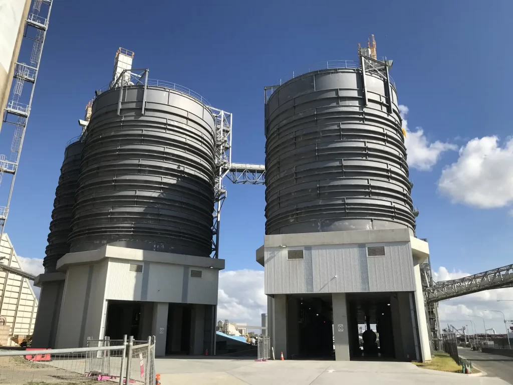 a large metal silos with a blue sky showcasing heavy industries